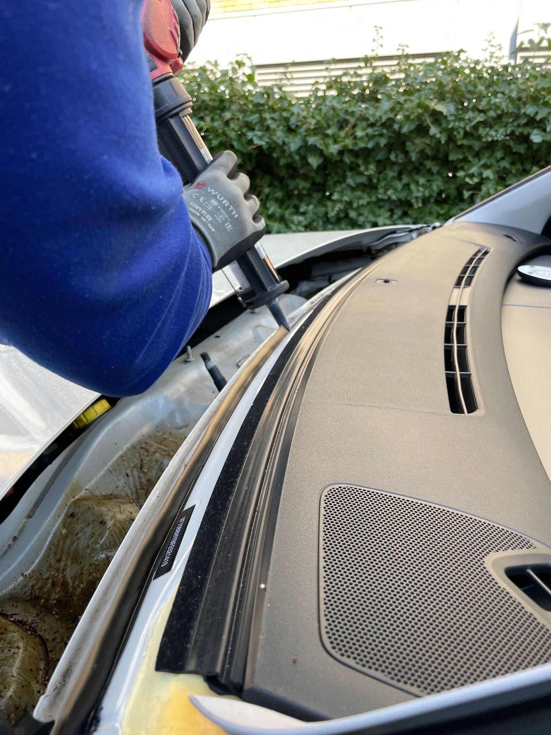 Technician fitting a new windshield onto a car dashboard