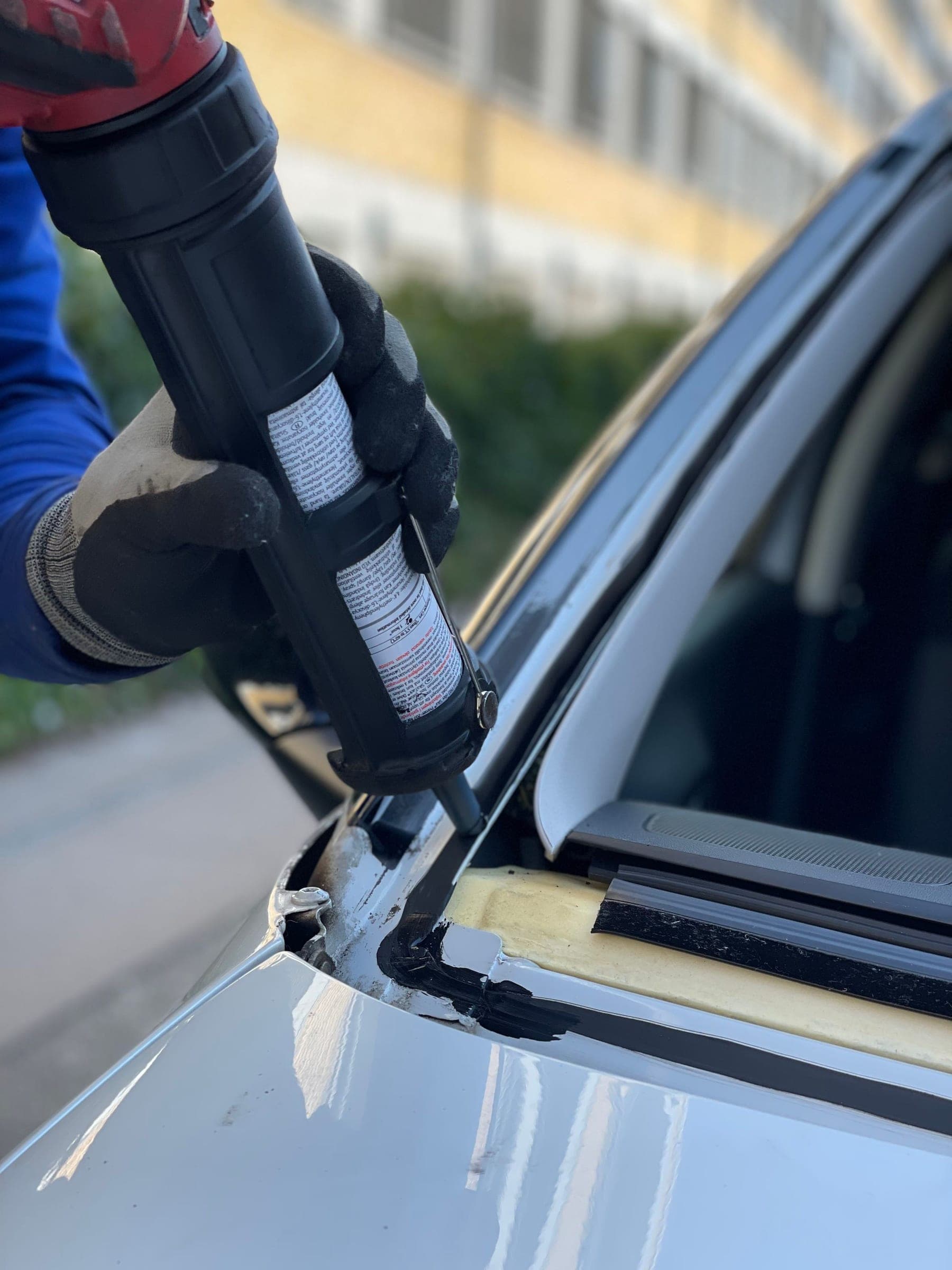 Windshield replacement in Billings: auto glass technician running a bead of urethane along the windshield opening