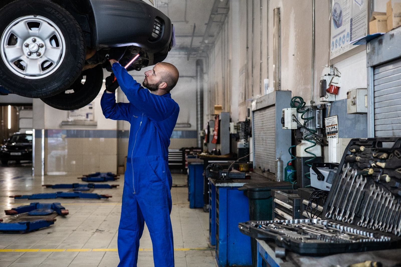 Technician checking a raised vehicle in a well lit auto shop